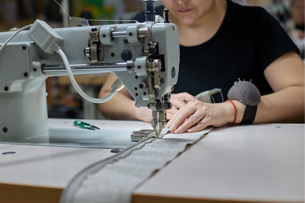 seamstress sewing fabric together using sewing machine wearing black shirt